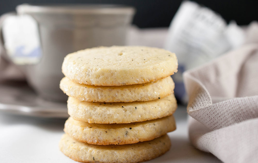 Earl Grey cookies on a rustic plate, garnished with tea leaves and served with a cup of tea.