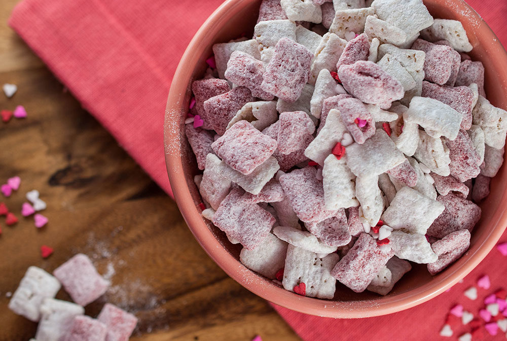 An appetizing bowl of healthy Muddy Buddies featuring whole grain cereal, dark chocolate, and powdered sugar, perfect for a wholesome breakfast or snack.